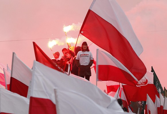 Members of right-wing groups light up flares during a march by some thousands of people, hosted by President Andrzej Duda that marked 100-years since Poland regained independence in Warsaw, Poland, Su ...