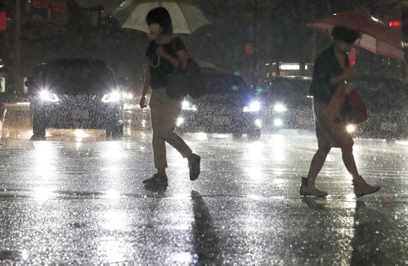 People holding umbrella make their way through heavy rain in Fukuoka, western Japan, Thursday, Aug. 12, 2021.(Kyodo News via AP)