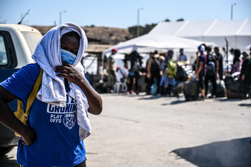 epa08679170 Asylum seekers wait with their belongings as refugees and migrants from the destroyed Moria camp wait to enter into the new temporary camp near Kara Tepe on Lesbos island, Greece, 18 Septe ...