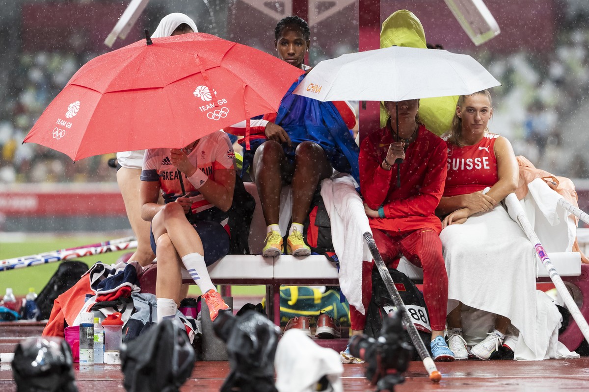 Angelica Moser of Switzerland, right, waits with other athletes during a rain break in the women's athletics pole vault qualification at the 2020 Tokyo Summer Olympics in Tokyo, Japan, on Monday, ...