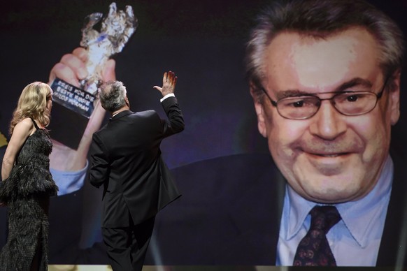 epa05803455 Festival director Dieter Kosslick (R) stands next to presenter Anke Engelke (L) and waves to former Berlinale bear winner, Czech film director Milos Forman (on the screen) during the closi ...