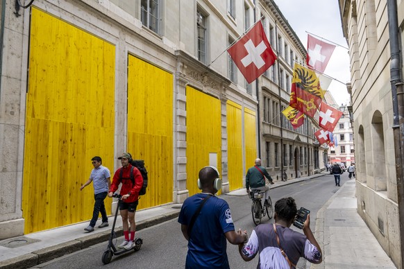 Passers-by walk past the entrance of the General Secretariats of the various cantonal departments of Geneva boarded up with wooden panels installed to protect the facade ahead of demonstrations agains ...