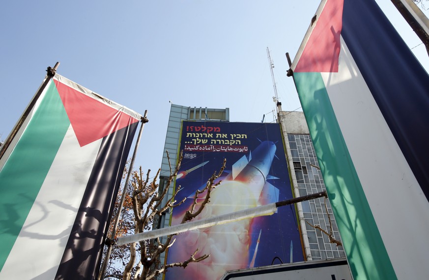 epa11082355 Palestinian flags and a billboard depicting Iranian missiles with a message in Persian and Hebrew reading: &#039;prepare your coffins&#039;, hangs on a building at Palestine square in Tehr ...