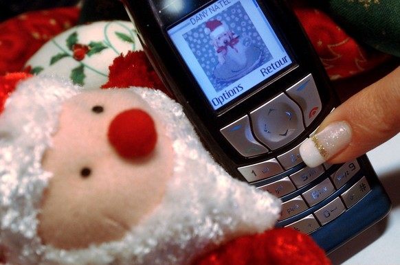 Une femme souhaite un Joyeux Noel en ecrivant un MMS sur sont natel ce vendredi 26 decembre 2003 a Bursinel, Vaud. Nouveau record pour les SMS, 42 millions de petits messages ont ete transmis durant l ...