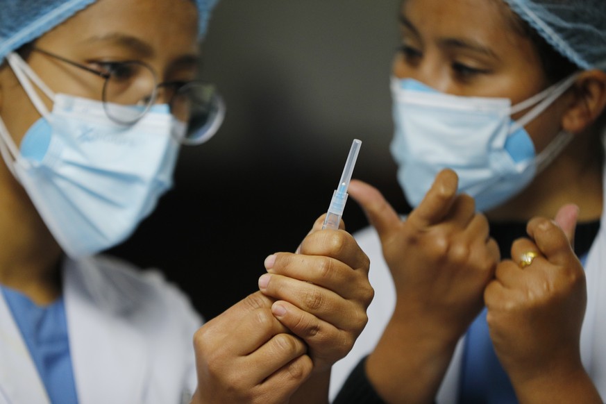 FILE - In this Jan. 27, 2021, file photo, a Nepalese health worker, right, instructs another on administering COVID-19 vaccine at Teaching Hospital in Kathmandu, Nepal. Neighboring India gifted Nepal  ...