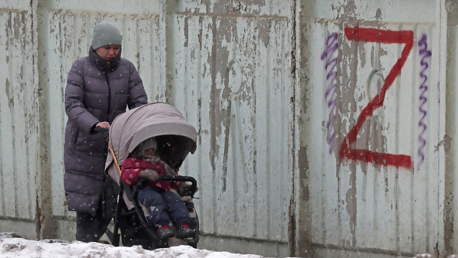 epa10439897 A woman pushes a stroller in front of a graffiti with a letter Z in support of the Russian army, in Moscow, Russia, January 30, 2023. The letters Z, V and O, painted on Russian military ...