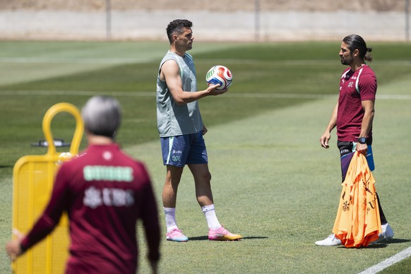 Switzerland's Granit Xhaka, back left, talks to assistant coach Davide Calla, while head coach Murat Yakin removes a dummy, during a training session of the Swiss national soccer team at the SDJA ...