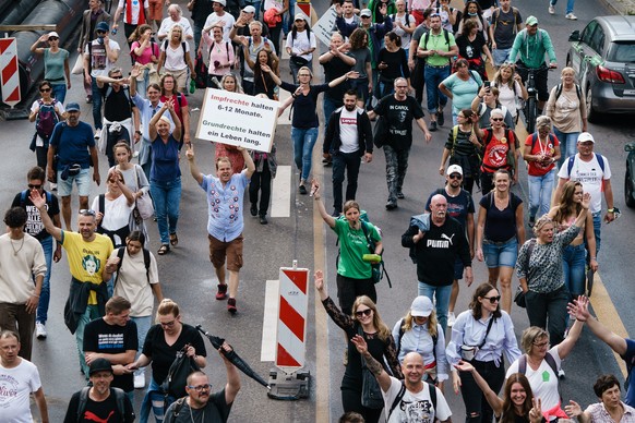 epa09386205 Demonstrators march on the streets during an unauthorized protest against the coronavirus measures, in Berlin, Germany, 01 August 2021. Unannounced rallies were held despite Berlin police  ...