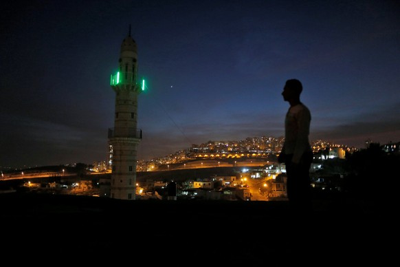 A man stands near a mosque opposite to a neighborhood in east Jerusalem November 13, 2016. REUTERS/Ammar Awad