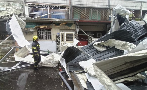 In this photo released by Hualien County Fire Department, police check a blown roof destroyed by the wind of Typhoon Kong-rey in Hualien County, eastern Taiwan, Thursday, Oct. 31, 2024. (Hualien Count ...