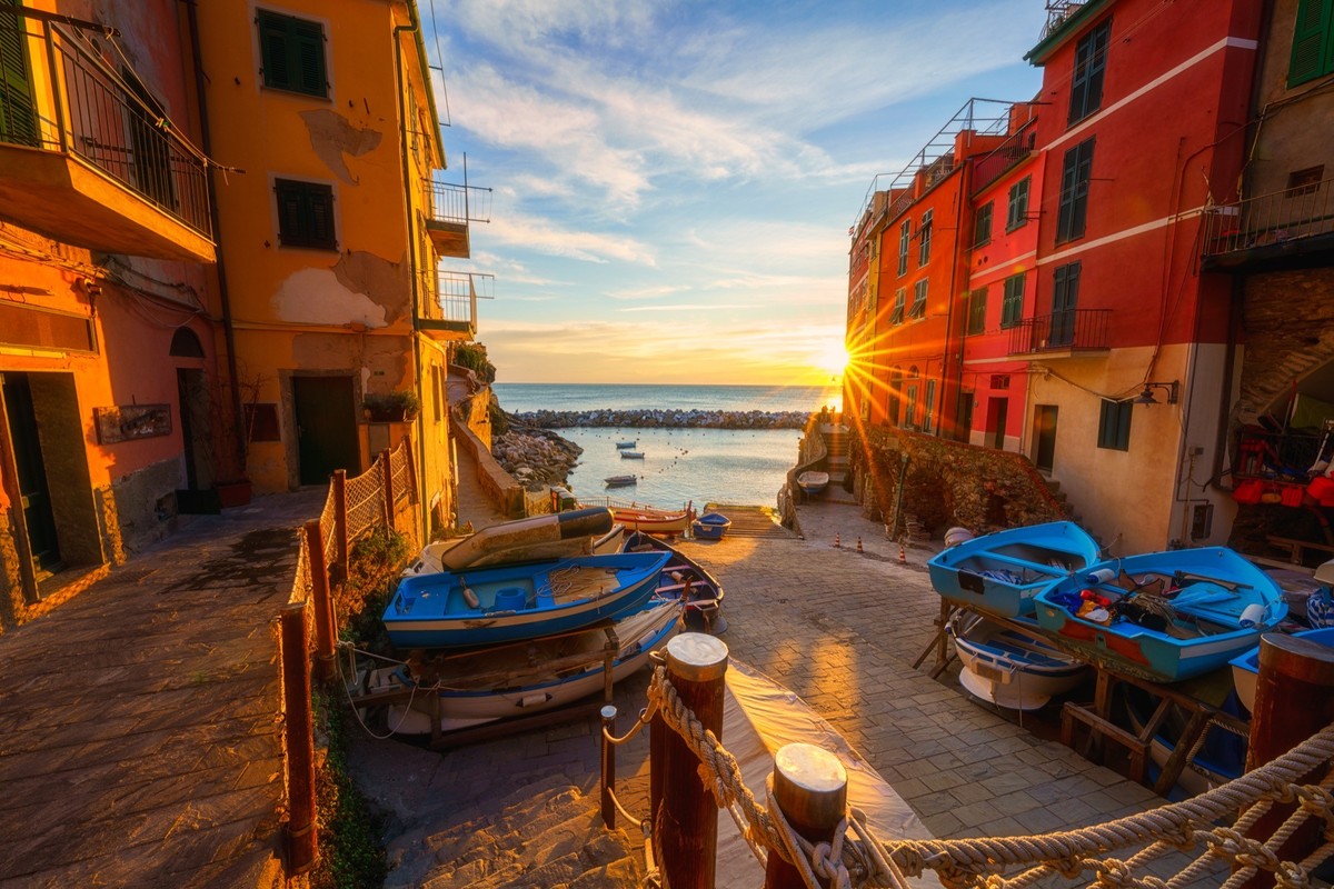 Riomaggiore city view, old village with medieval architecture, colorful houses, sea and fishing boats at sunset, Cinque Terre National Park, Liguria region of Italy. Outdoor travel background