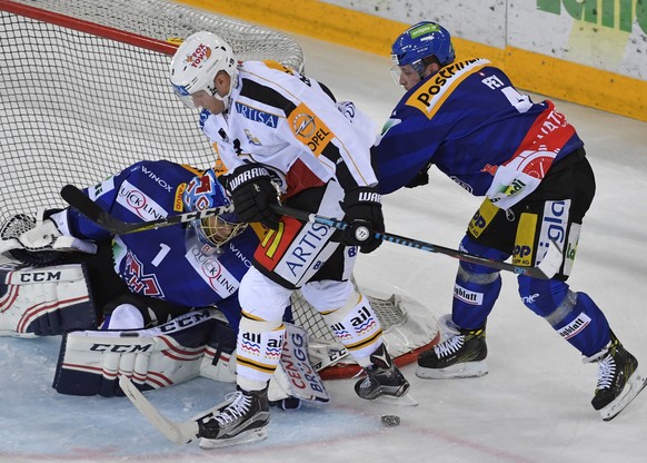 Der Tessiner Tony Martensson, Mitte, und die Bieler Torhueter Jonas Hiller und Kevin Fey, von links, kaempfen um den Puck beim Eishockeyspiel der National League A zwischen dem EHC Biel und dem HC Lug ...