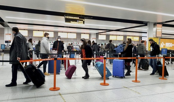 FILE - In this Dec. 20, 2020, file photo, passengers queue for check-in at Gatwick Airport in West Sussex, England, south of London. The United States will require airline passengers from Britain to g ...