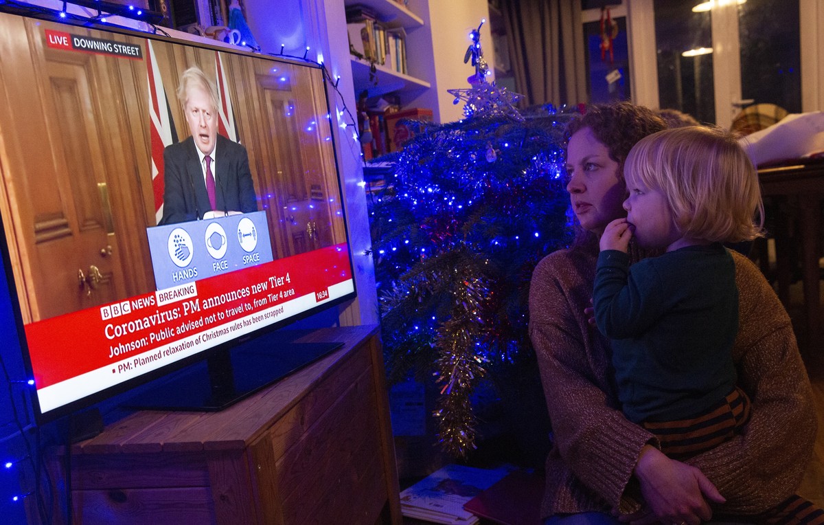 epa08894231 Leanne Hall and her son Alex watch as Britain's Prime Minister Boris Johnson delivers a televised statement in London, Britain, 19 December 2020. Britain's Prime Minister Boris J ...