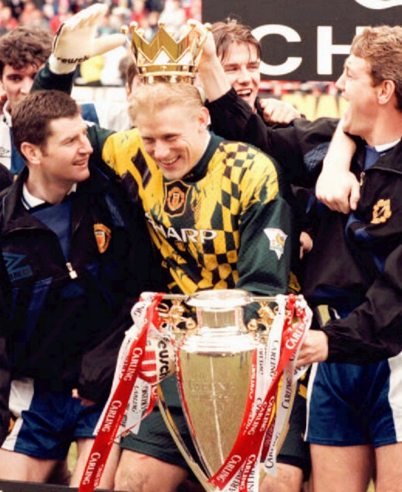 Manchester United&#039;s Danish goalkeeper Peter Schmeichel is flanked by celebrating teammates Dennis Irwin, left and Steve Bruce, right, after United clinched the English Premier League title by bea ...