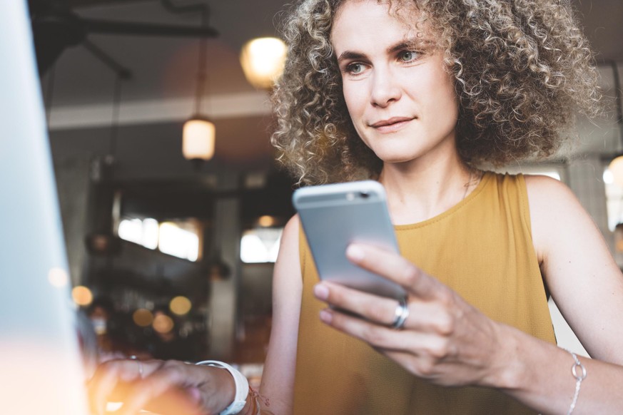 Frau mit Smartphone in Restaurant.