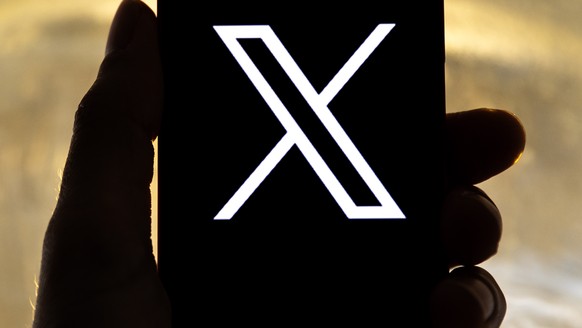 epa10772439 An illustration pictures shows a user holding a mobile phone displaying the 'X' logo, in Los Angeles, California, USA, 27 July 2023. Twitter announced on 23 July that it will reb ...