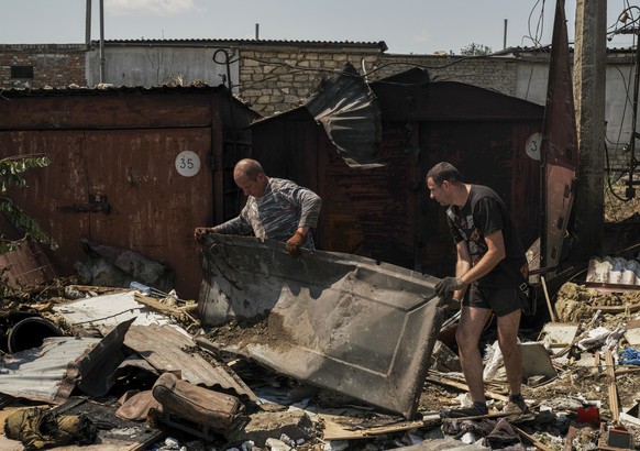 epa10041008 Men remove debris of destroyed private garages after shelling at a residential area in Mykolaiv, southern Ukraine, 29 June 2022. The Head of the Mykolaiv Regional Military Administration,  ...