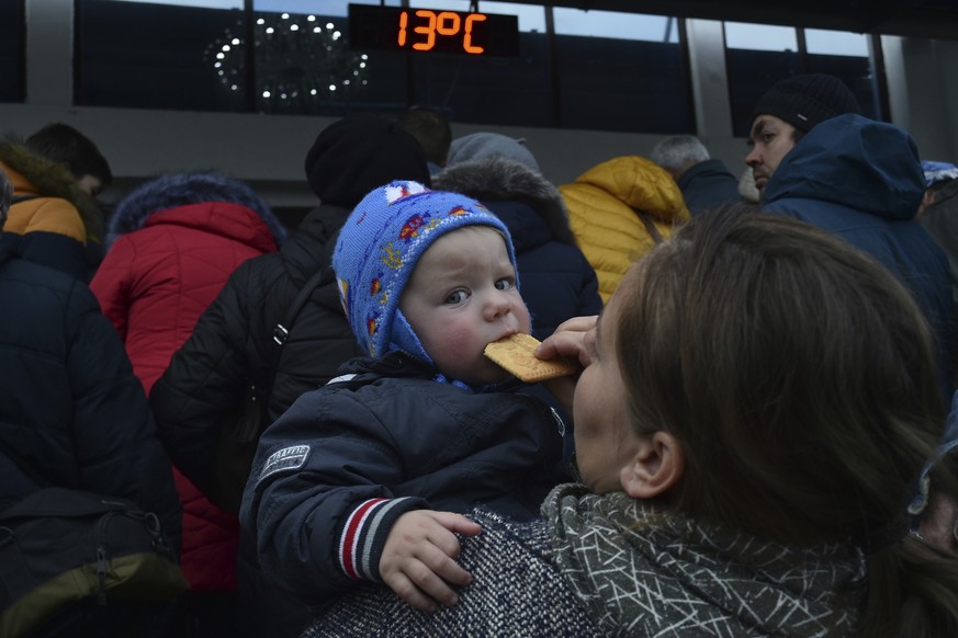 FILE - A woman hods her child as other evacuees from Kherson gather upon their arrival at the railway station in Dzhankoi, Crimea, on Oct. 21, 2022. Russian authorities, who initially dismissed talk o ...