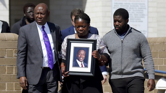 Caroline Ouko, mother of Irvo Otieno, holds a portrait of her son as she walks out of the Dinwiddie Courthouse with attorney Ben Crump, center left, and her older son, Leon Ochieng, in Dinwiddie, Va., ...