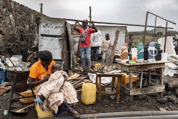 KEYPIX - epa11889173 A woman holds a child as people dismantle tents to salvage materials in a refugee camp in Bulengo, Democratic Republic of Congo, 11 February 2025. Displaced persons living in the  ...