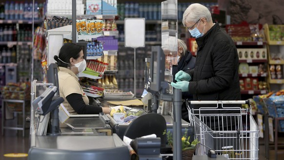 Supermarket employees and customers wear protective masks in a shop in Vienna, Austria, Wednesday, April 1, 2020. In Austria protective masks should be worn in shops from Wednesday on. The Austrian go ...