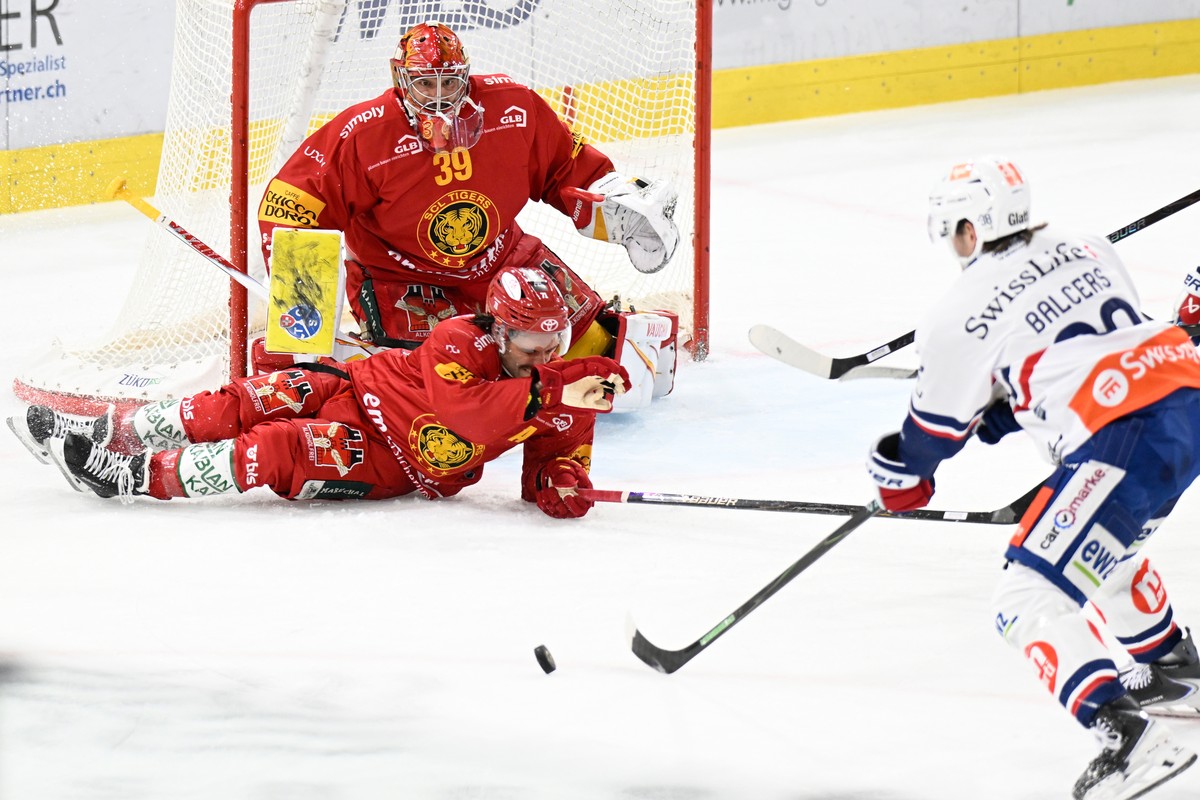 Tigers Goalie Luca Boltshauser, und Tigers Julian Schmutz, wehren sich gegen den Schuss von Lions Rudolfs Balcers, rechts, beim Eishockey-Qualifikationsspiel der National League, zwischen den SCL Tige ...