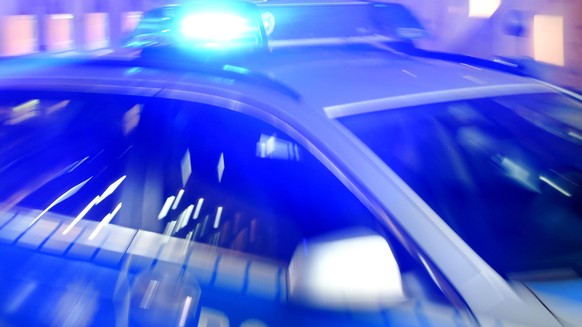 ARCHIV - 06.08.2015, Schleswig-Holstein, Flensburg: ILLUSTRATION - Ein Streifenwagen der Polizei steht mit eingeschaltetem Blaulicht auf der Stra
