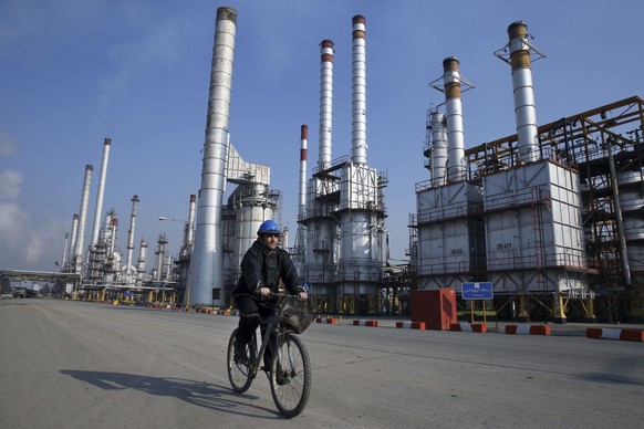 FILE - In this Dec. 22, 2014 file photo, an Iranian oil worker rides his bicycle at the Tehran oil refinery, south of the capital Tehran, Iran. State-run Press TV quoted the Iranian Oil Minister Bijan ...