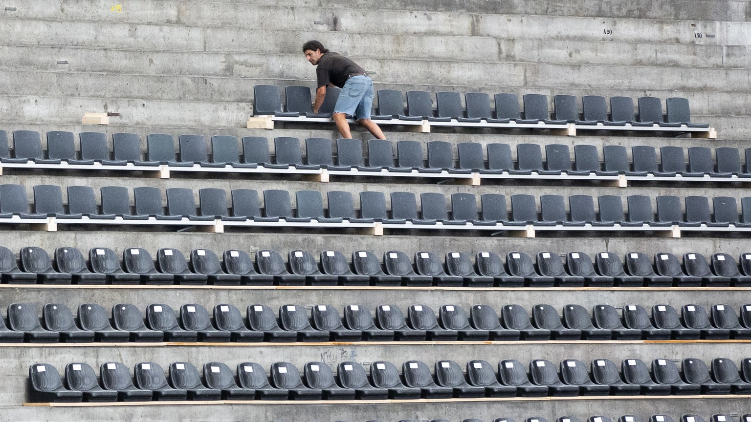 Ein Arbeiter montiert Sitze auf der Stehplatzrampe in der Postfinance Arena, am Dienstag, 15. September 2020 in Bern. (KEYSTONE/Peter Klaunzer)