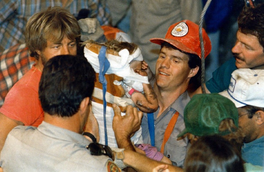 FILE - In this October 1987 file photo, rescue workers carry 18-month-old Jessica McClure to safety in Midland, Texas after she was trapped for 58 hours after she plunged 22 feet into an abandoned wat ...