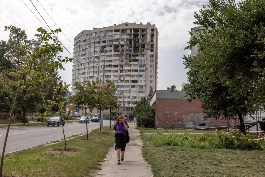epa10133468 A woman walks next to a damaged residential building in Chernihiv, northern Ukraine, 22 August 2022. Chernihiv region was one of the most affected regions in Ukraine, becoming a battlefiel ...