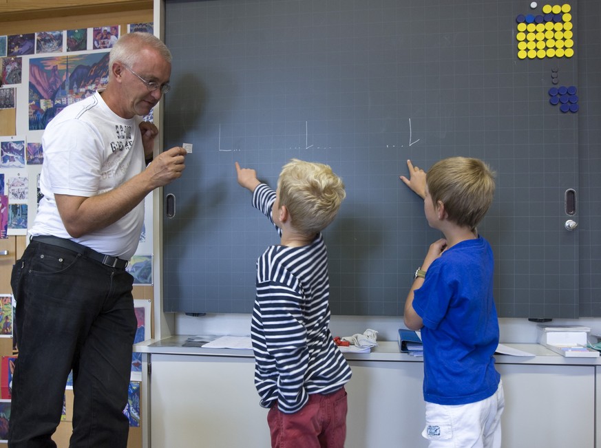 Weg von der antiquierten Schnürlischrift, hin zur zeitgemässen Basisschrift – Lehrer und Schüler an einer Schweizer Primarschule.