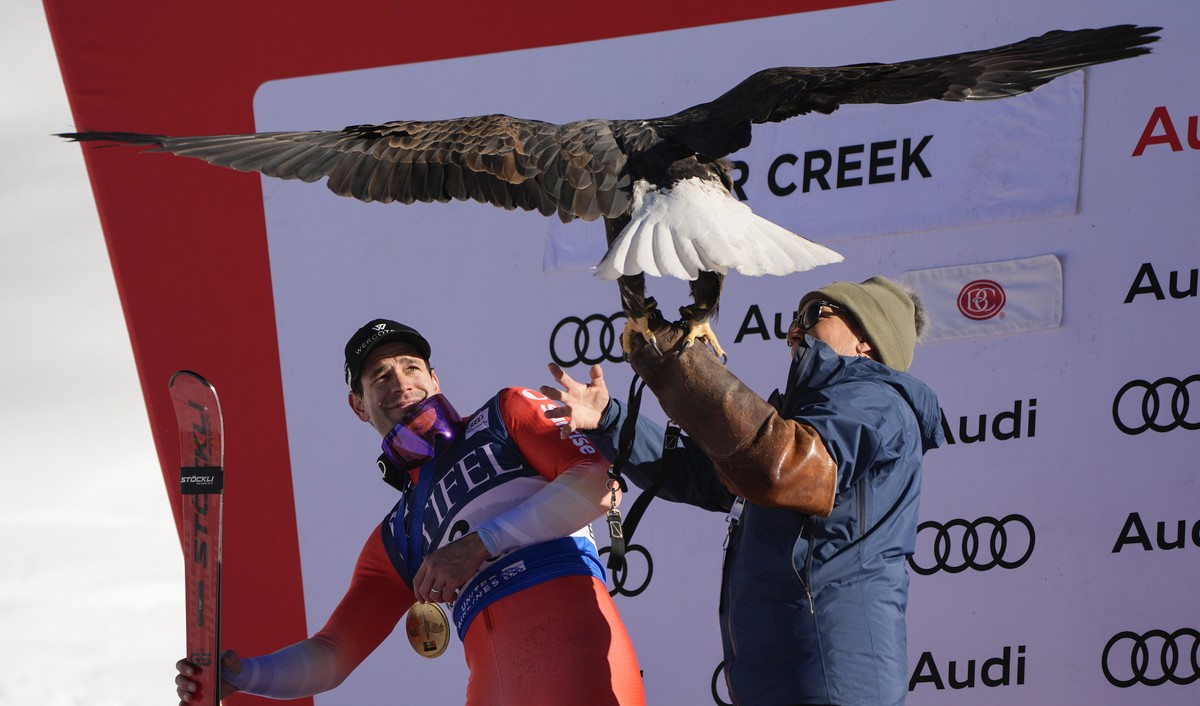First place finisher Switzerland's Thomas Tumler, left, reacts as he poses for photos with a bald eagle after a men's World Cup giant slalom skiing race, Sunday, Dec. 8, 2024, in Beaver Cree ...