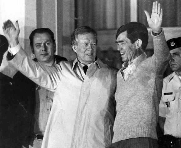 FILE - Former U.S. President Jimmy Carter, who had negotiated for the hostages release right up to the last hours of his presidency, waves to the crowd while putting his other hand around the shoulder ...