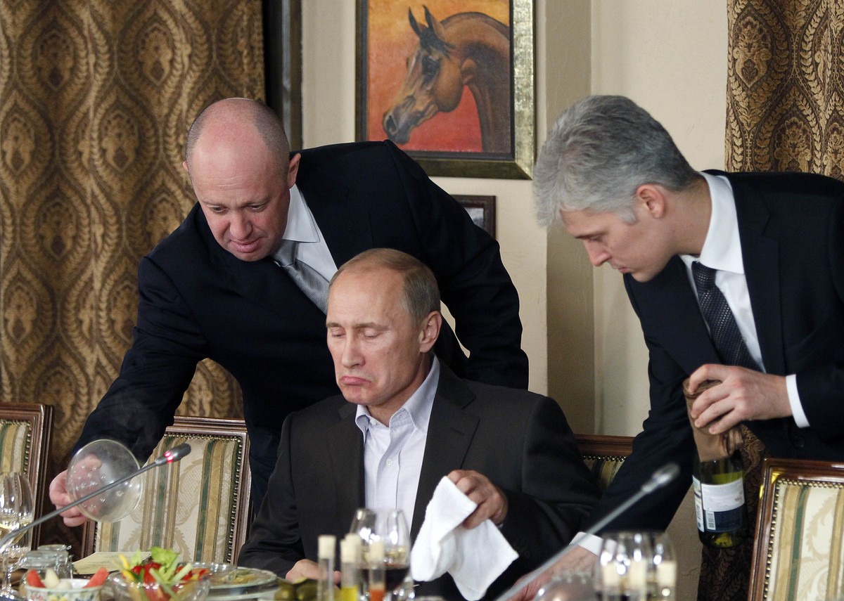 FILE - In this Friday, Nov. 11, 2011 file photo, businessman Yevgeny Prigozhin, left, serves food to Russian Prime Minister Vladimir Putin, center, during dinner at Prigozhin's restaurant outside ...
