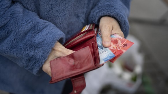 Eine Person zieht waehrend eines Marktes auf dem Hevetiaplatz in Zuerich Schweizer Banknoten aus ihrem Portemonnaie, fotografiert am Freitag, 16. Februar 2024. (KEYSTONE/Gaetan Bally)