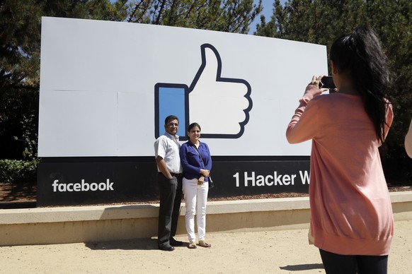 In this Aug. 31, 2016 photo, visitors take photos in front of the Facebook logo outside of the company&#039;s headquarters in Menlo Park , Calif. There&#039;s a quirky twist in tourism emerging amid t ...