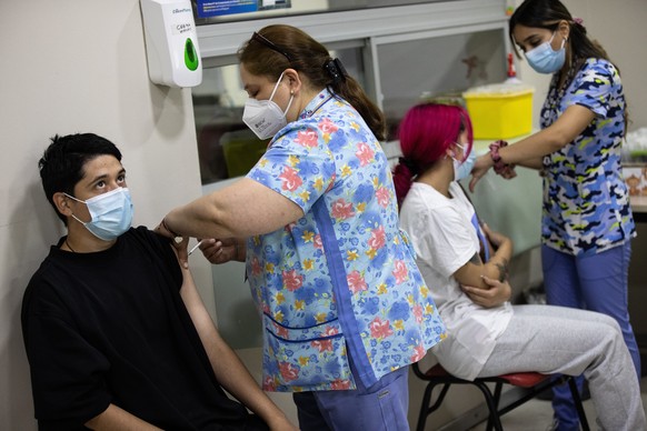 epa09677295 Two people receive a dose of the vaccine against Covid-19, at a vaccination center in Santiago, Chile, 10 January 2022. On 10 January, Chile becomes the second country in the world after I ...