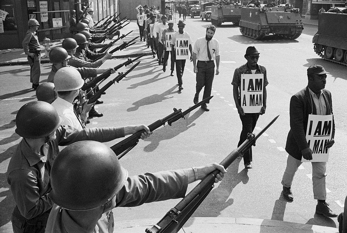 U.S. National Guard troops block off Beale Street as Civil Rights marchers wearing placards reading, "I AM A MAN" pass by on March 29, 1968. It was the third consecutive march held by the gr ...