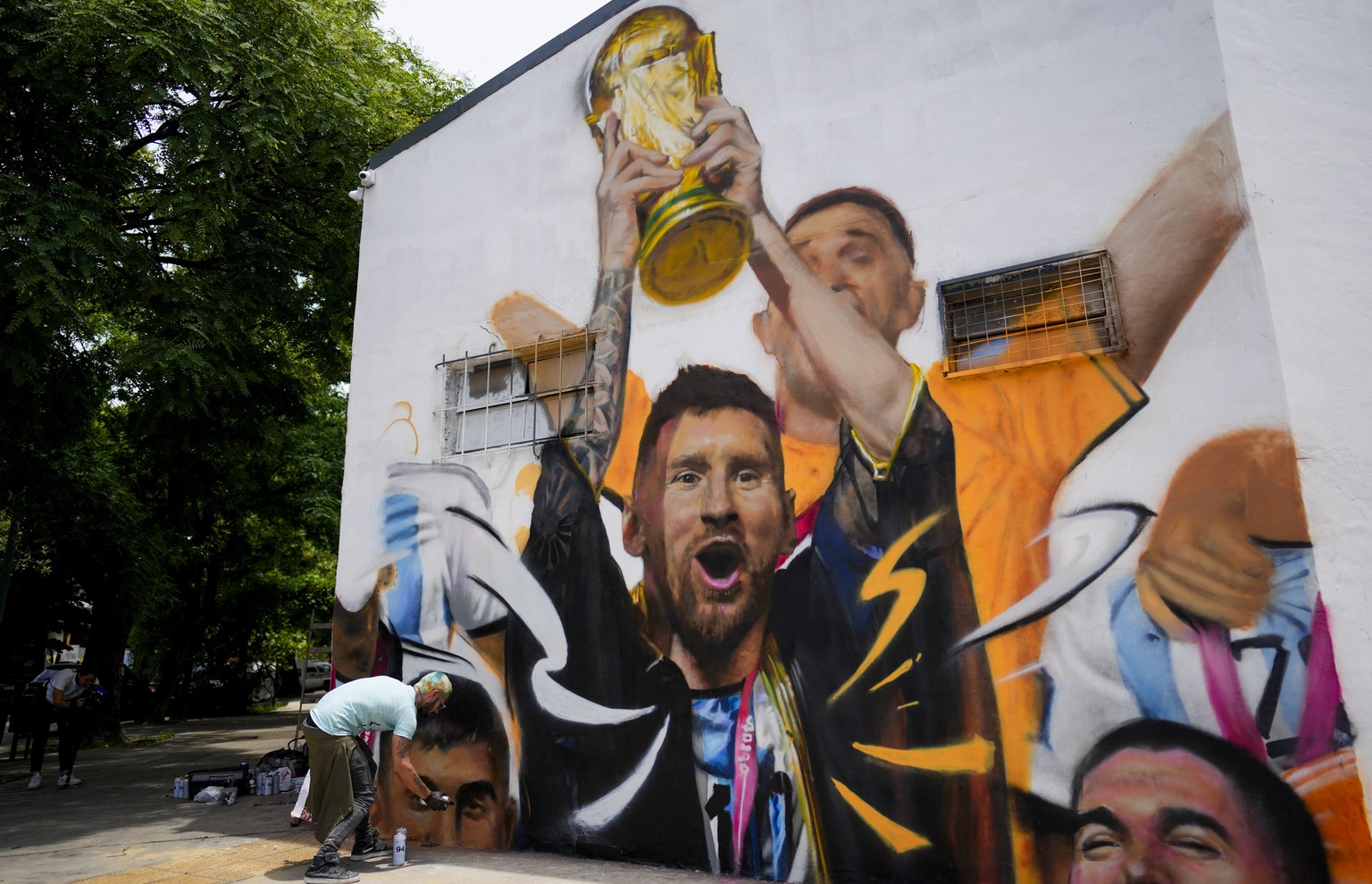 Artist Maxi Bagnasco paints a mural featuring Argentine soccer player Lionel Messi holding up the World Cup trophy after the team won the title, in Buenos Aires, Argentina, Thursday, Dec. 22, 2022. (A ...