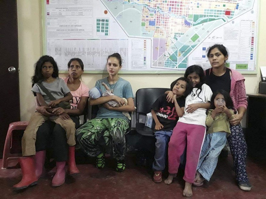 In this photo provided by Peru&#039;s police press office, Spanish citizen Patricia Aguilar, third from left, holds her baby at a police station, alongside two other Peruvian women and their children, ...