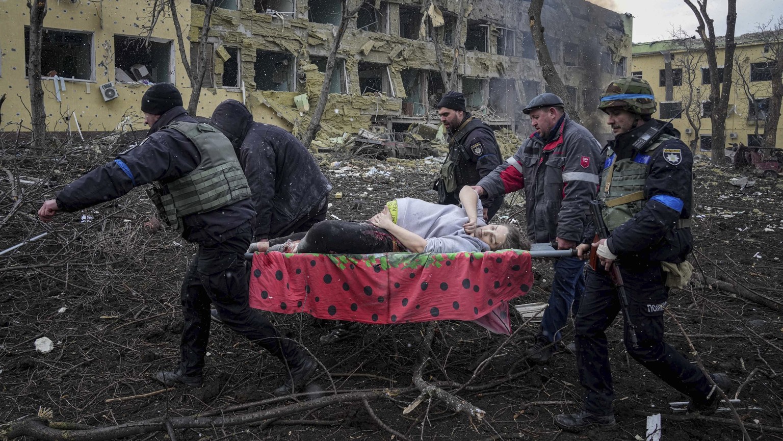 FILE - Ukrainian emergency employees and volunteers carry an injured pregnant woman from a maternity hospital that was damaged by shelling in Mariupol, Ukraine, March 9, 2022. The woman and her baby d ...