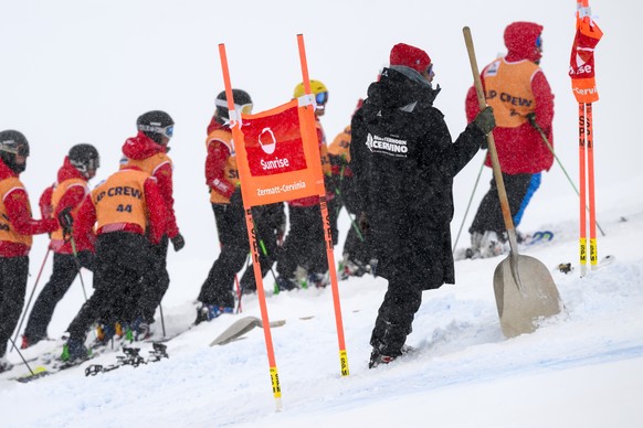 epa10968128 Volunteers remove snow from the slopes as the men's downhill training race was canceled due to heavy snow on the new ski trail "Grandma Becca" in Alpine skiing FIS Ski ...