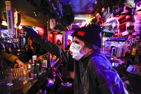 FILE - Bartender Cassandra Paris takes a farewell shot at an early closing time at 169 Bar with patrons, Monday, March 16, 2020, in New York.  Restaurants, bars and gyms will have to close at 10 p.m. across New York state in the latest effort to curb the spread of the coronavirus, Gov. Andrew Cuomo announced Wednesday, Nov. 11. Cuomo said the new restrictions, which go into effect Friday, are necessary because new coronavirus infections have been traced to those types of activities.  (AP Photo/John Minchillo)