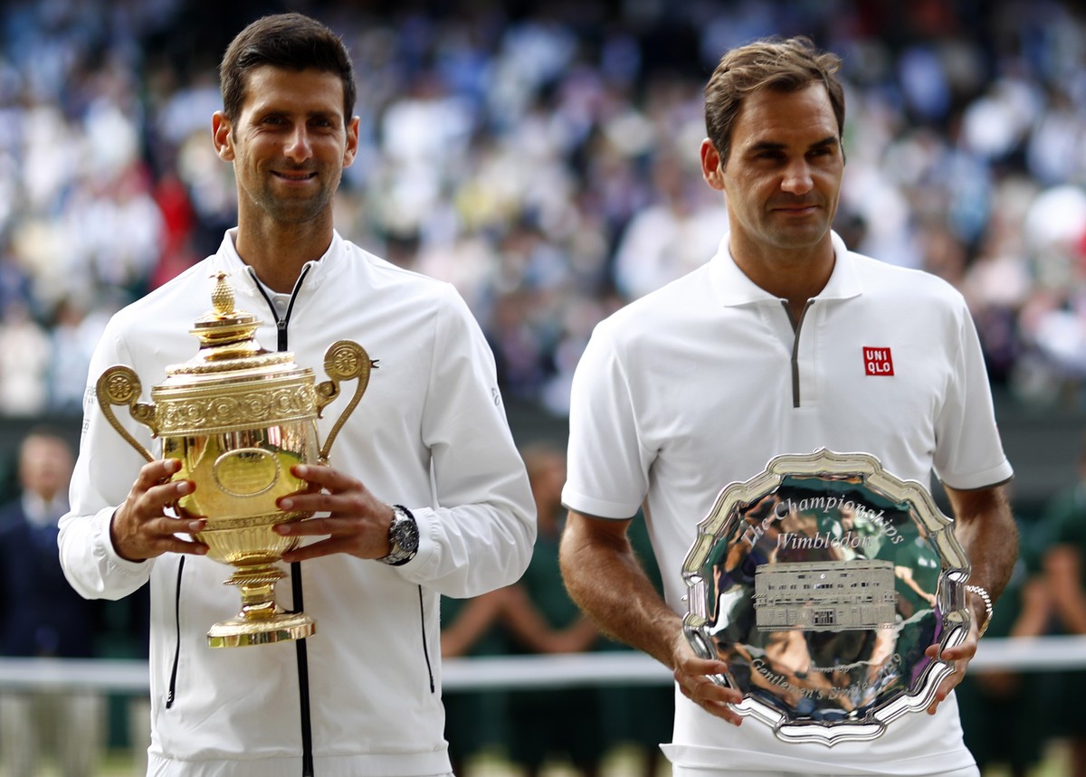 epa07717317 Novak Djokovic of Serbia (L) with the championship trophy after defeating Roger Federer of Switzerland (R) in the men's final of the Wimbledon Championships at the All England Lawn Te ...