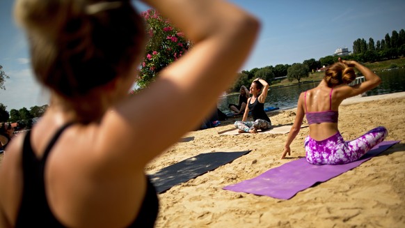 epa06103339 Yoga instructor Birgit Brandstetter gives a lesson at the so-called Copa Beach, next to the Danube discharge channel in Vienna, Austria, 22 July 2017. Temperatures in Austria rose up to 30 ...