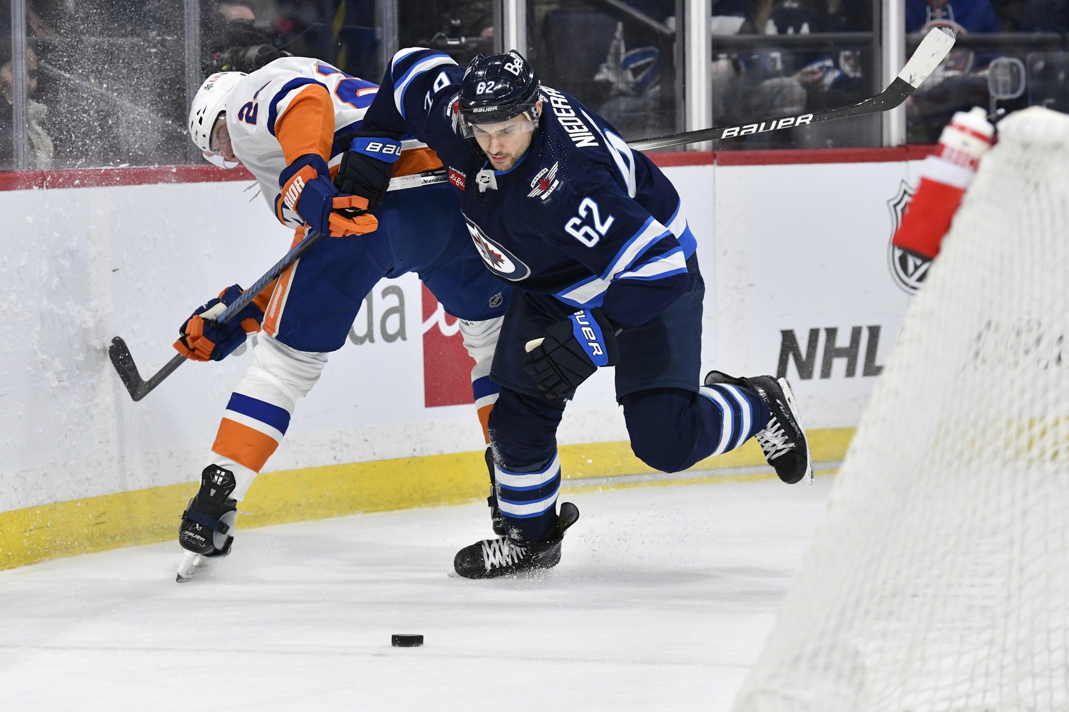 New York Islanders&#039; Scott Mayfield (24) and Winnipeg Jets&#039; Nino Niederreiter (62) compete for the puck behind the net during the second period of an NHL hockey game Tuesday, Jan. 16, 2024, i ...