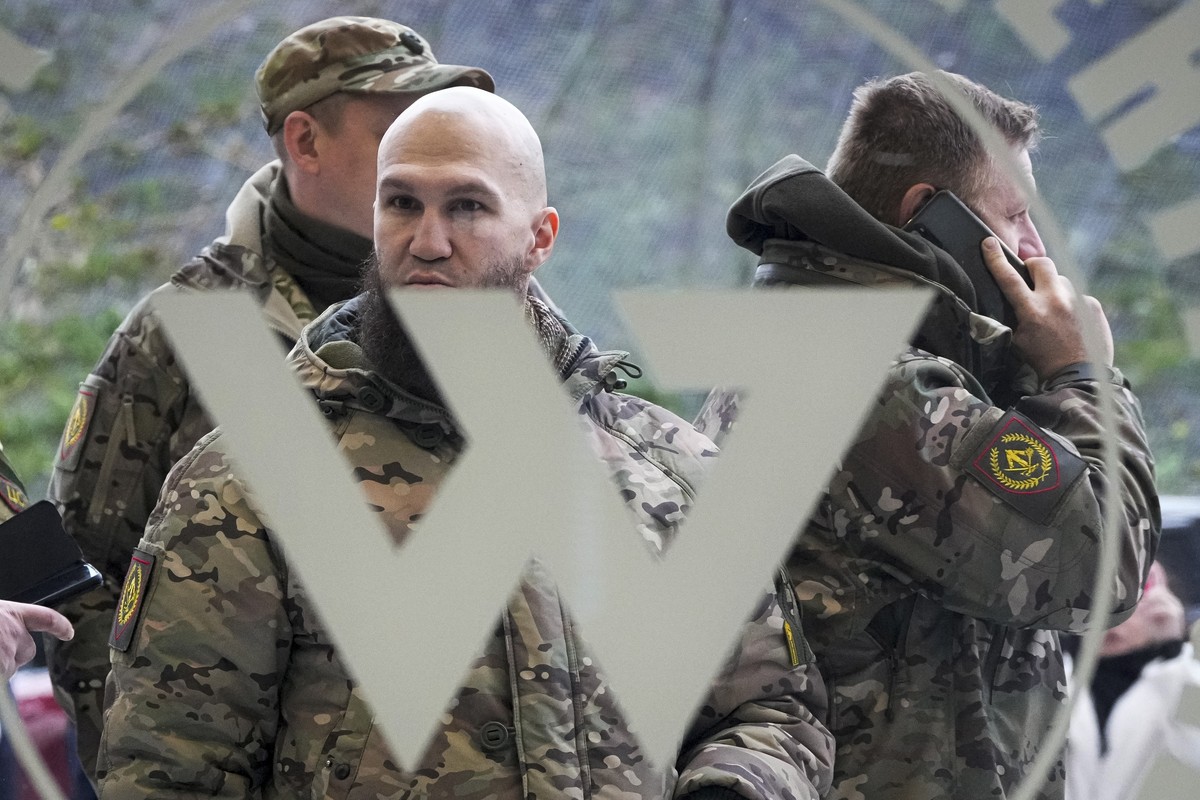 FILE - Visitors wearing military camouflage stand at the entrance of the 'PMC Wagner Centre', which is associated with businessman and founder of the Wagner private military group Yevgeny Pr ...
