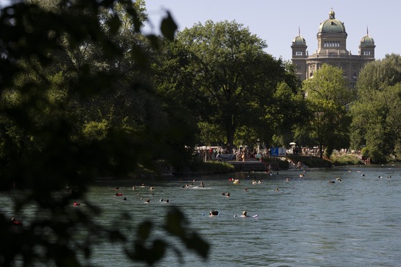 KEYPIX - Menschen geniessen an einem Hitzetag die Sonne und schwimmen in der Aare mit dem Bundeshaus im Hintergrund, am Donnerstag, 18. Juni 2026 in Bern. Seit Donnerstag gibt der Bund Hitzewarnungen  ...